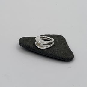Silver ring with a  layered design, displayed on a small dark gray stone against a light gray background.